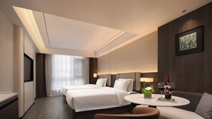 A hotel room with two beds, a sofa, a small table with wine glasses, and a TV.