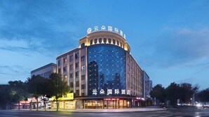A hotel with a modern glass facade, a prominent sign at the top, and a ground-level entrance with visible signage.