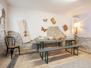 A rustic dining area with a stone wall, a wooden bench, a table, and a chair. - Queen Bee by Interhome (Ponzone)