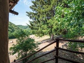 A wooden staircase leading to a stone wall, surrounded by lush greenery and trees. - La Baluna by Interhome (Priero)