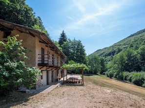 A rustic building with a balcony, surrounded by a natural landscape and a clear sky. - La Baluna by Interhome (Priero)