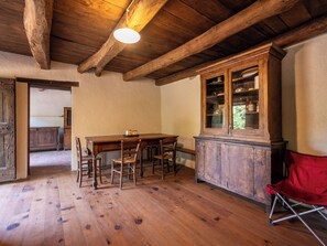 A rustic wooden dining area with a table and chairs, a cabinet with glass doors, and a red chair. - La Baluna by Interhome (Priero)