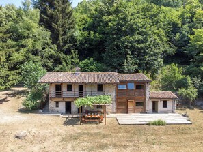 A rustic stone house with a tiled roof, a wooden porch, and a small garden area. - La Baluna by Interhome (Priero)