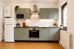 Eine Küche mit Kühlschrank, Mikrowelle, Backofen und einem Fenster mit Blick.
