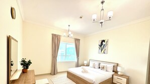 Een moderne slaapkamer met een groot bed, nachtkastjes, een spiegel, een potplant en een raam met gordijnen.