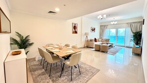 Een moderne woonkamer met een eethoek, grote ramen en een kroonluchter.