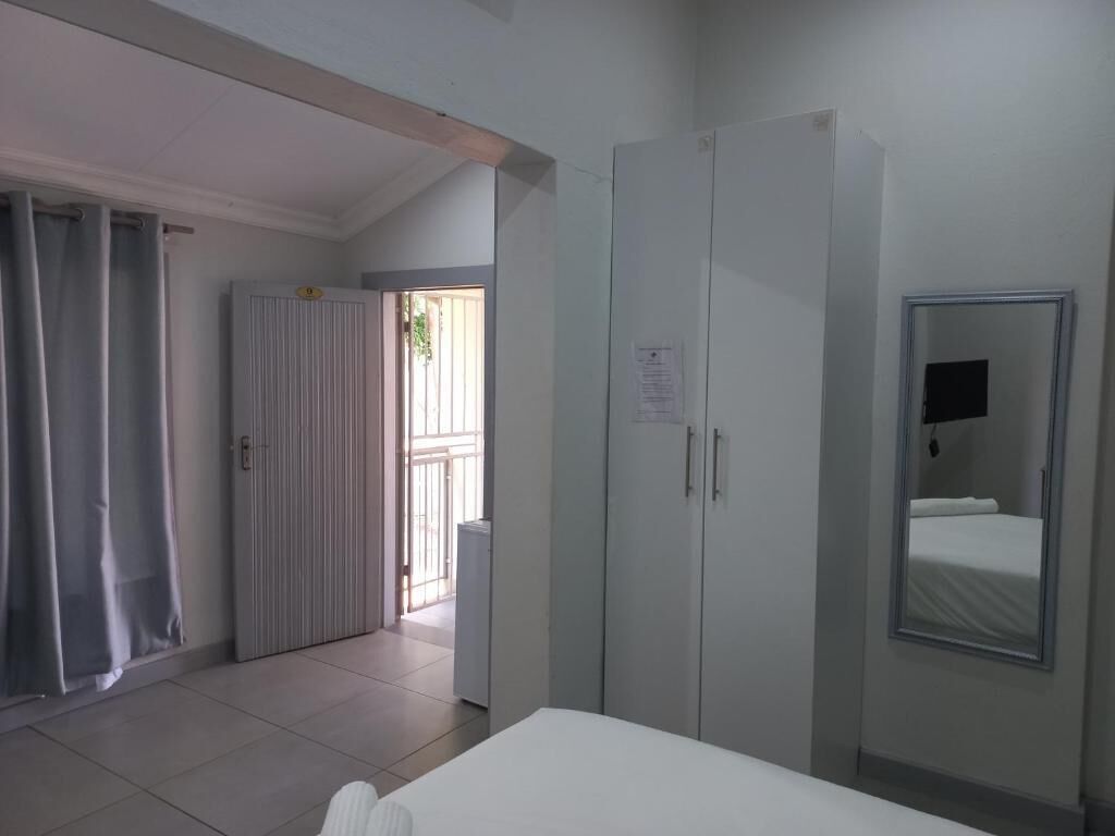 Une chambre d’hôtel comprenant un lit, une armoire, un miroir et une porte donnant sur un espace extérieur.