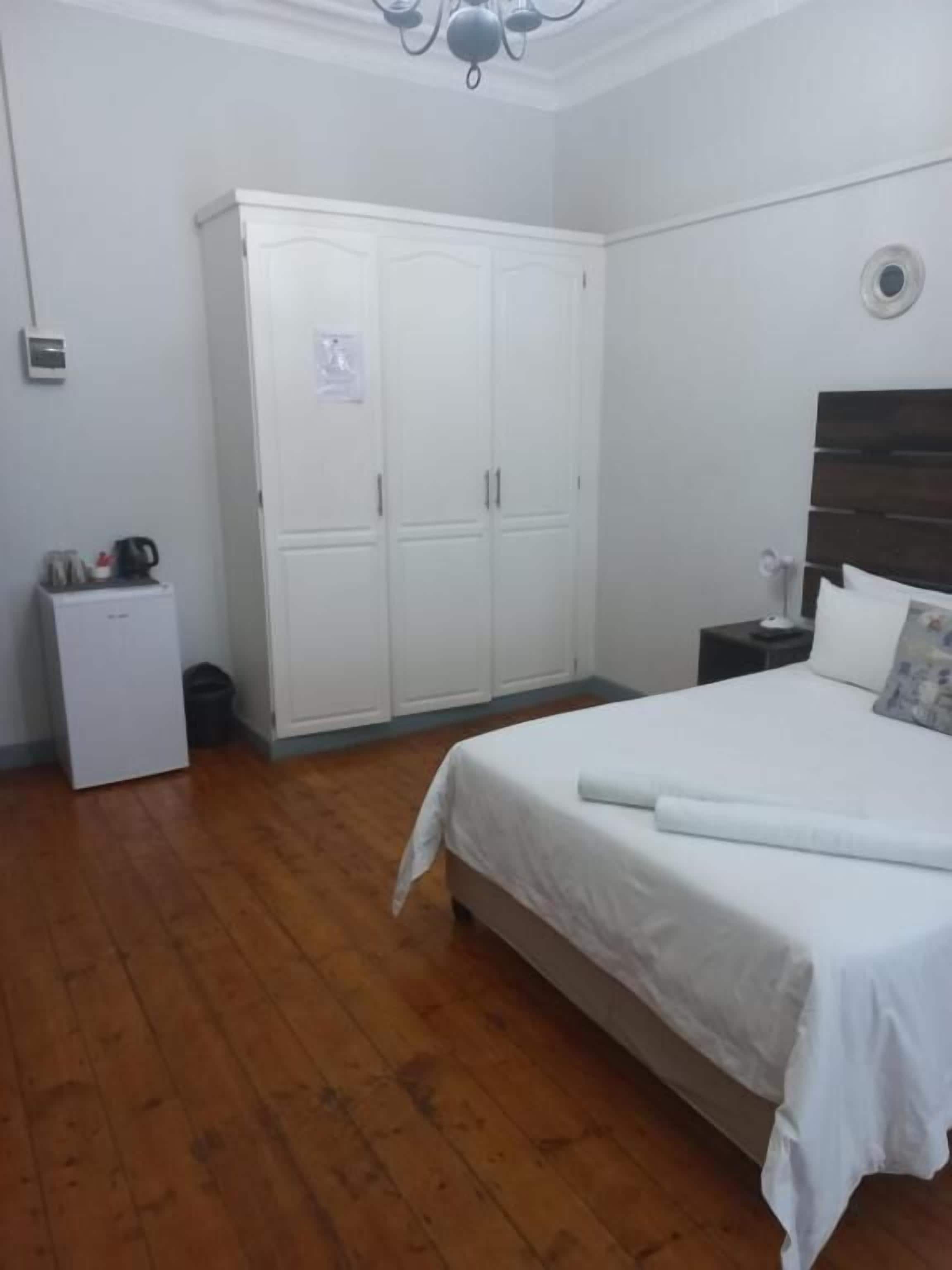 Une chambre à coucher comprenant un lit, une armoire, une table de chevet, une lampe et un luminaire au plafond.
