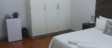 Un dormitorio con cama, armario, mesita de noche, lámpara y lámpara de techo.