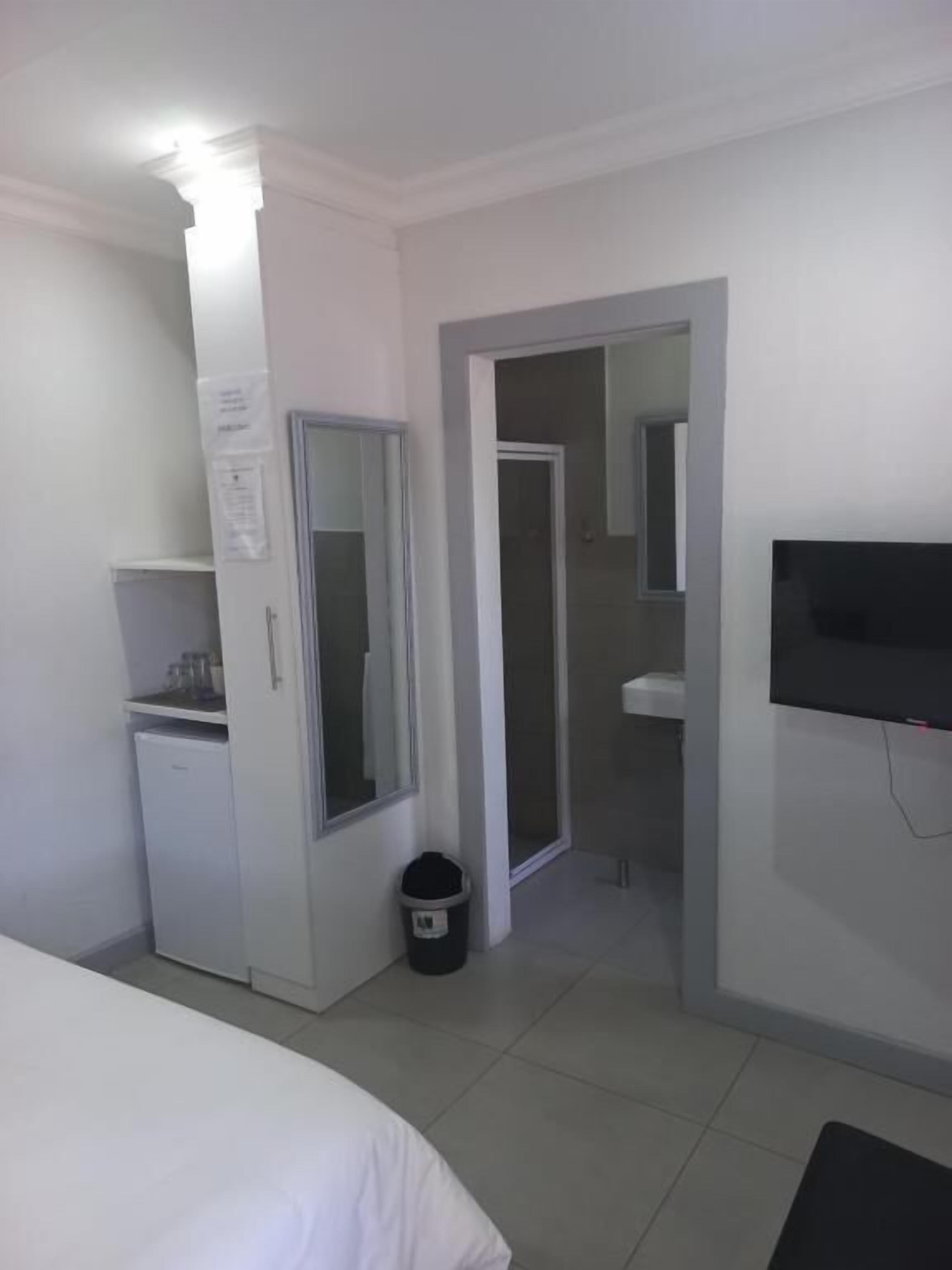 Hotelkamer met een bed, een bureau, een televisie, een spiegel en een deur naar de badkamer.