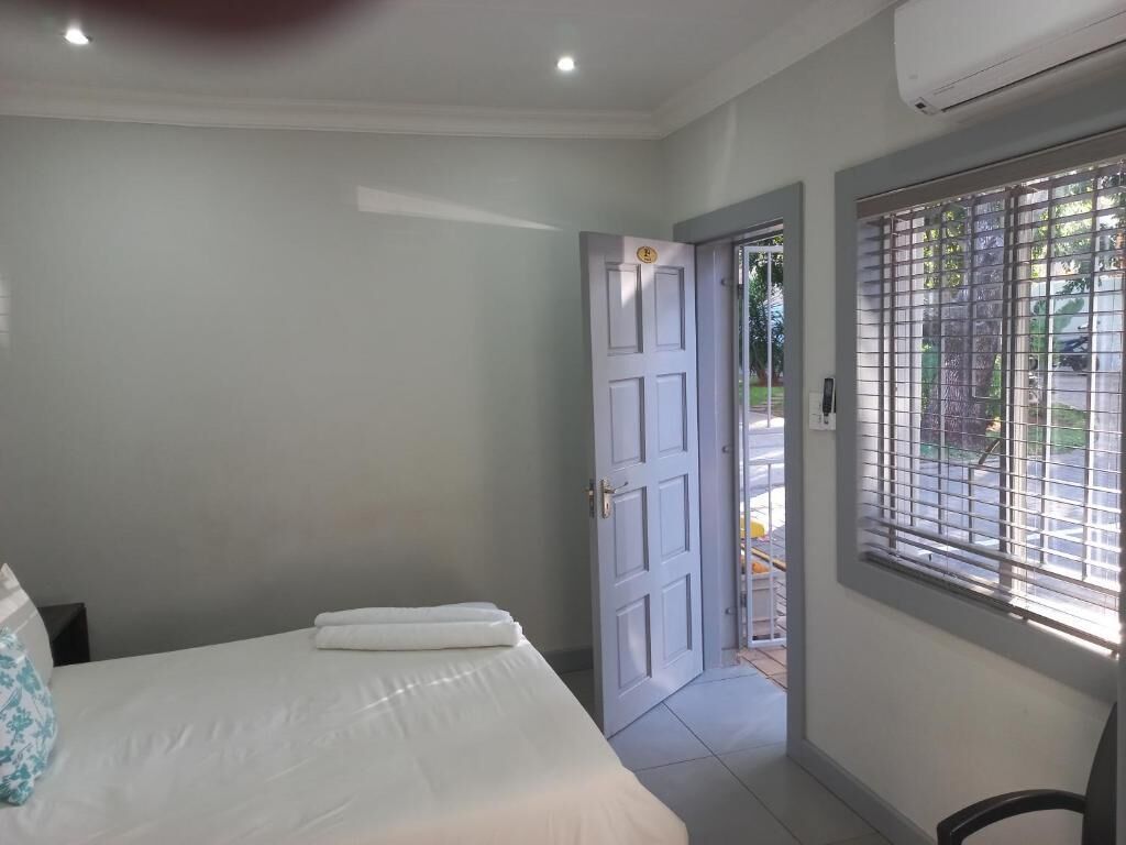 A bedroom with a bed, a door, and a window with blinds.