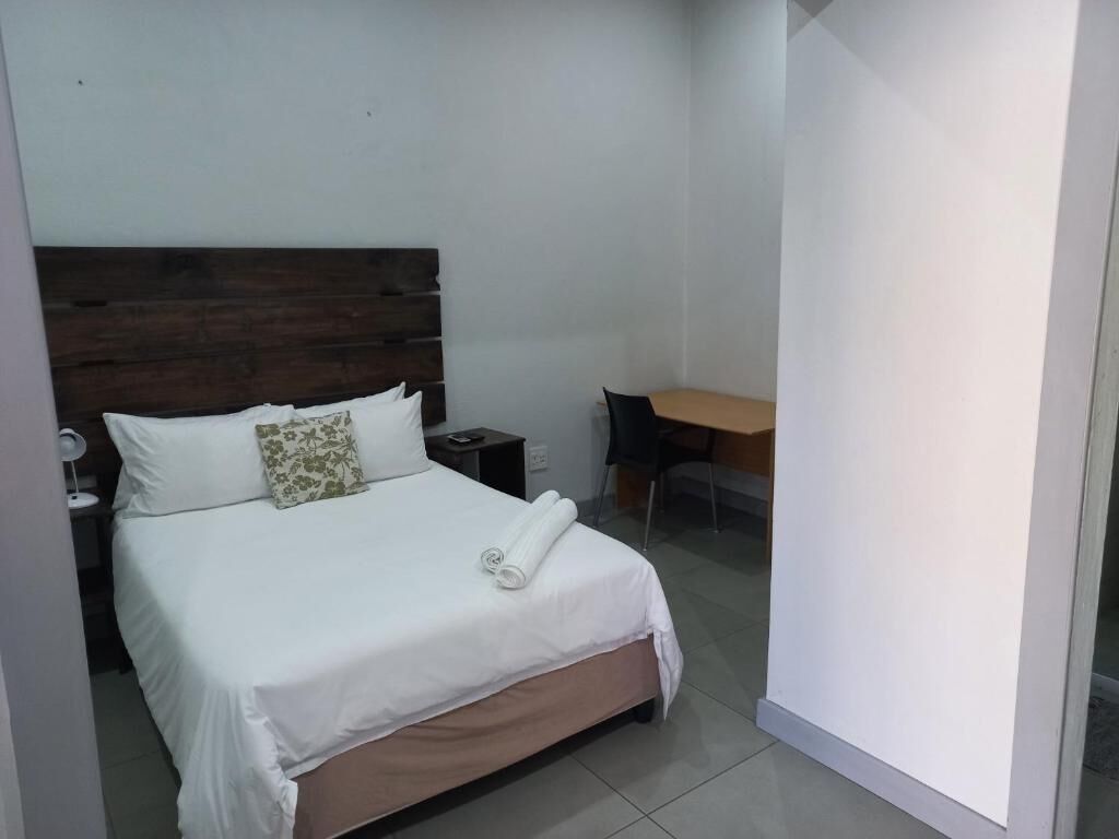 A bedroom with a bed, a desk, and a chair.