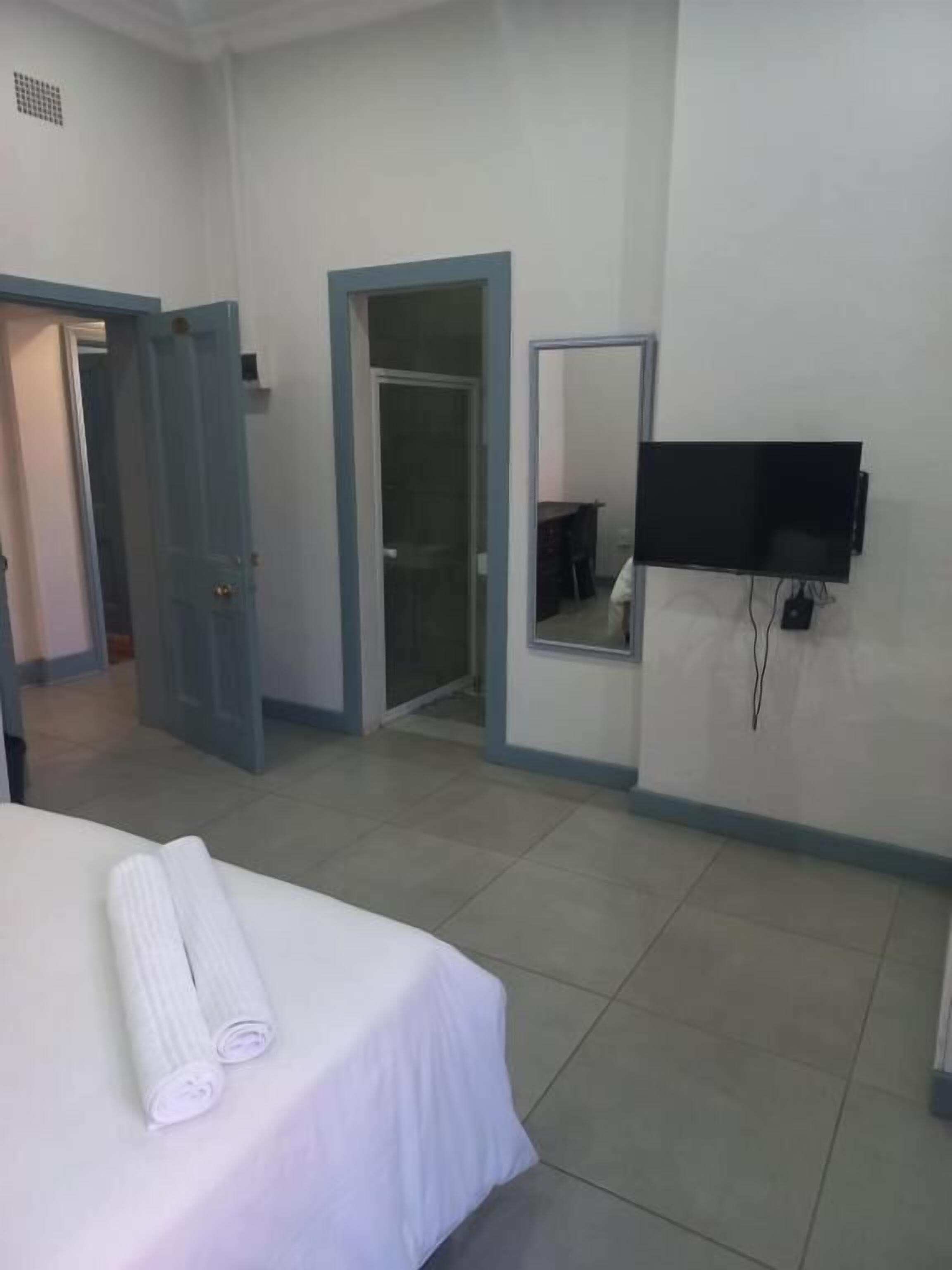 A hotel room with a bed, a TV mounted on the wall, and a door leading to another room.