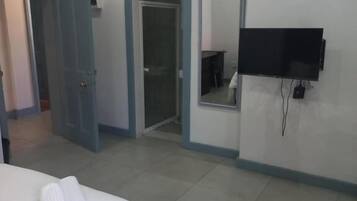 A hotel room with a bed, a TV mounted on the wall, and a door leading to another room.