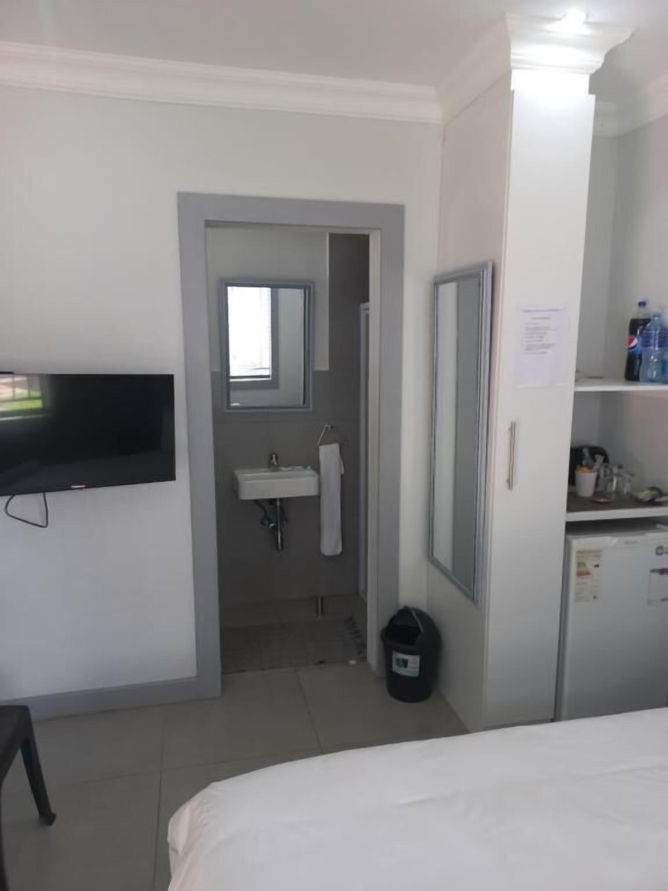 Una habitación de hotel con una cama, un televisor, un lavamanos y un espejo.