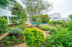 A modern house with a swimming pool, surrounded by lush greenery and a well-maintained garden. - Rosario’s Village 11 Taplow (Johannesburg)