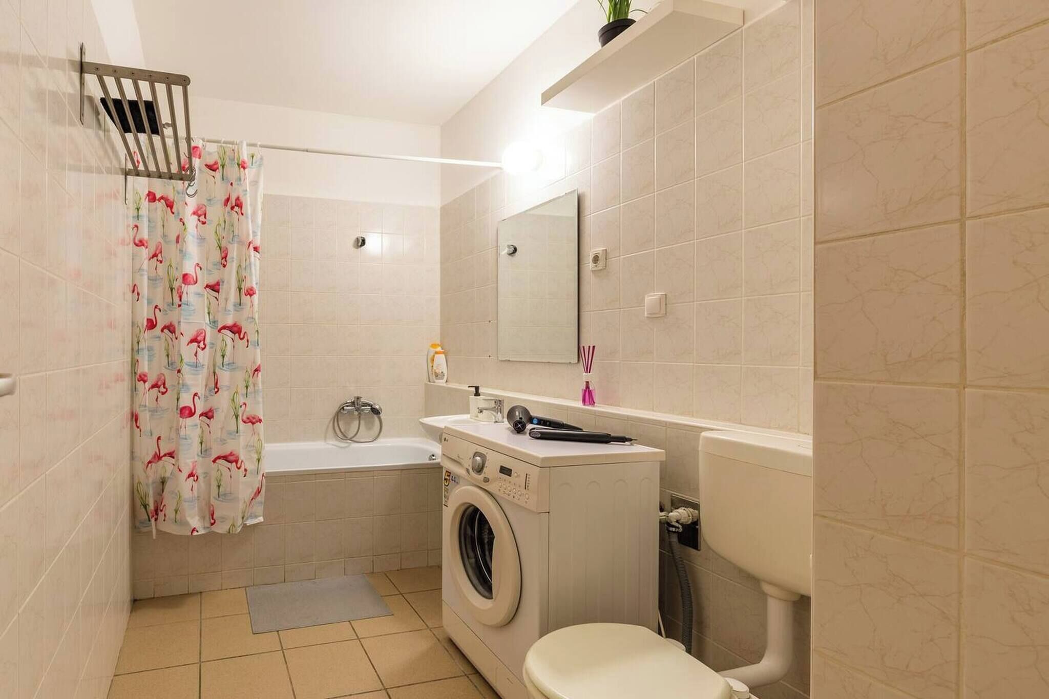 Un bagno con lavatrice, vasca da bagno, WC e specchio.