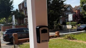 Un pal blanc amb un cadenat Master Lock negre penjant-hi.