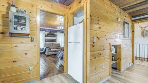 Ein Holzblockhaus-Interieur mit Küchenzeile, einem Kühlschrank und einem Esstisch.