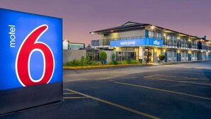A motel with a large sign displaying the number 6, a 'welcome' sign, and an 'office' sign.