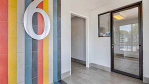 A hallway with a large number '6' on the wall, a glass door, and a tiled floor.