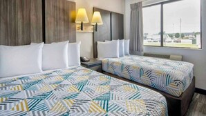 A hotel room with two beds, a large window, and a view of the outside.