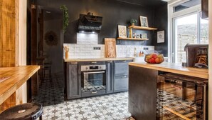 A modern kitchen with dark cabinetry, a central island, and a backsplash. - A Getaway in the Cotentin (Cherbourg-en-Cotentin)