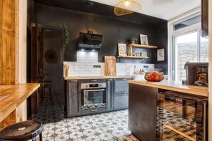 A modern kitchen with dark cabinetry, a central island, and a backsplash. - A Getaway in the Cotentin (Cherbourg-en-Cotentin)