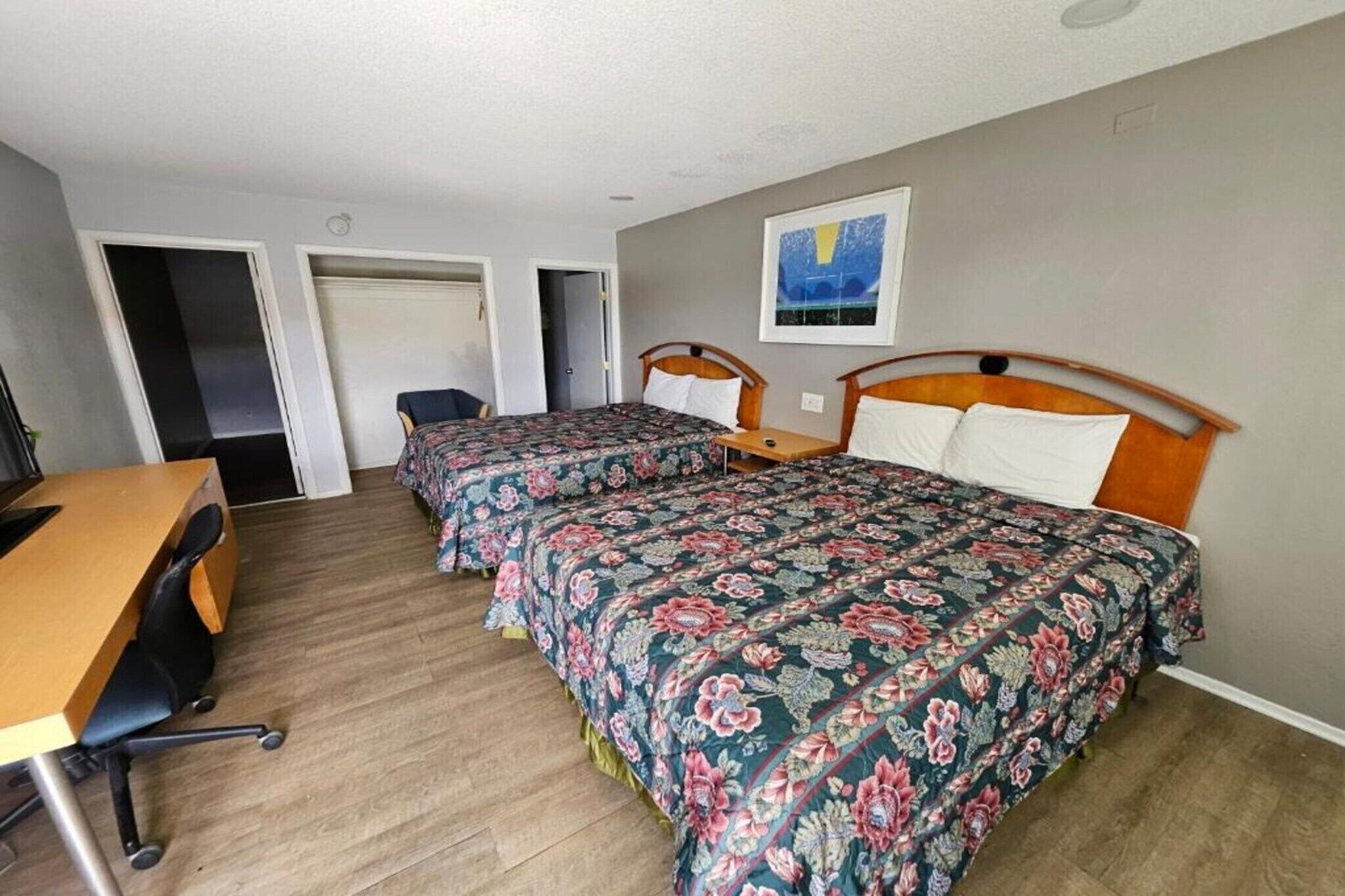 Une chambre d’hôtel avec deux lits simples, un bureau en bois et une chaise.