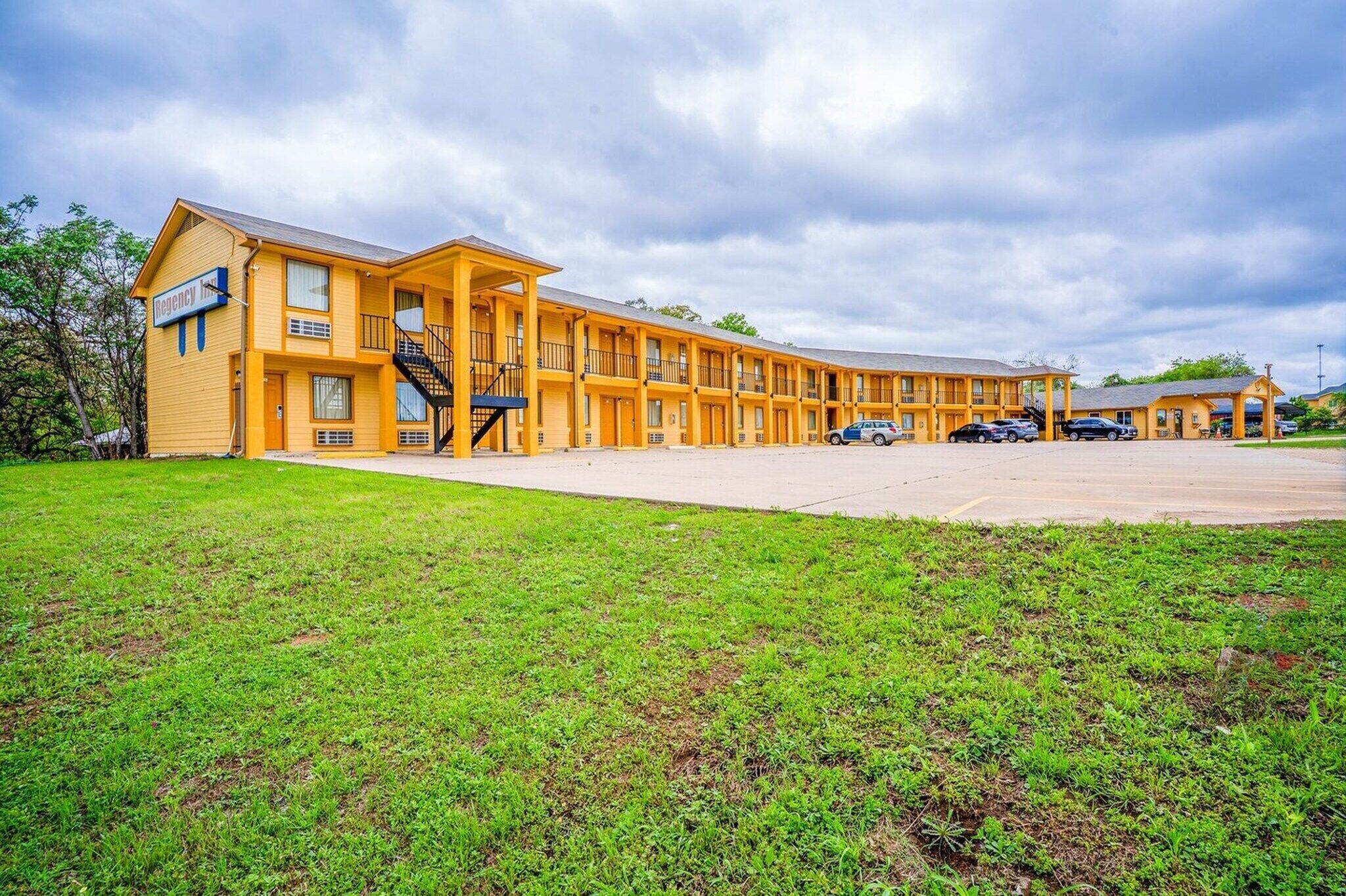 A motel with a central courtyard, multiple balconies, and a parking area.