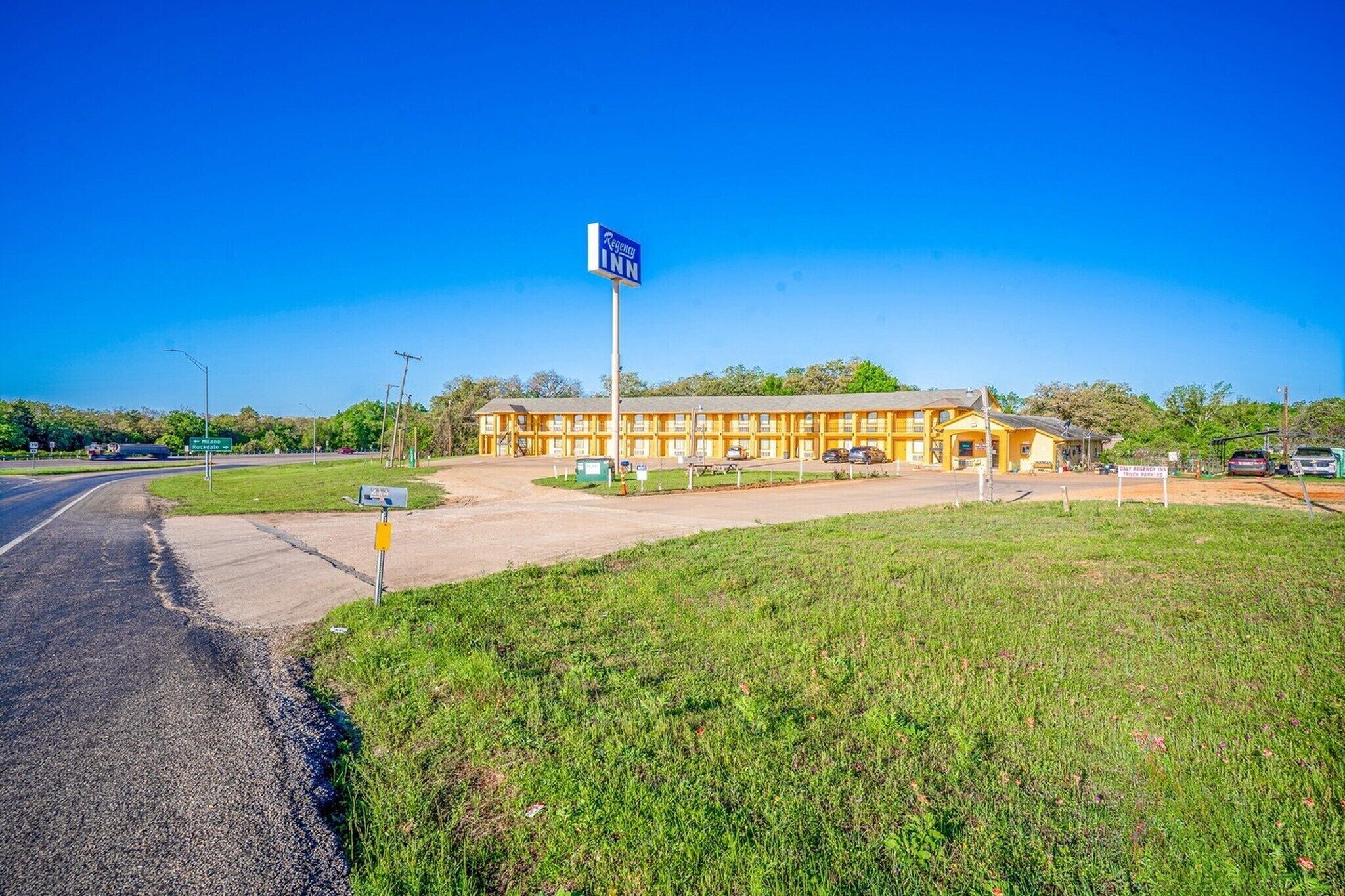 Un motel avec une grande enseigne, un parking et une pelouse devant.