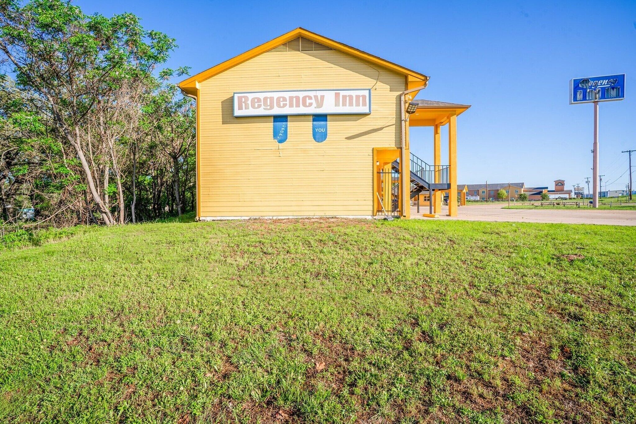 A yellow building with a sign reading 'Regency Inn' and a covered outdoor area.