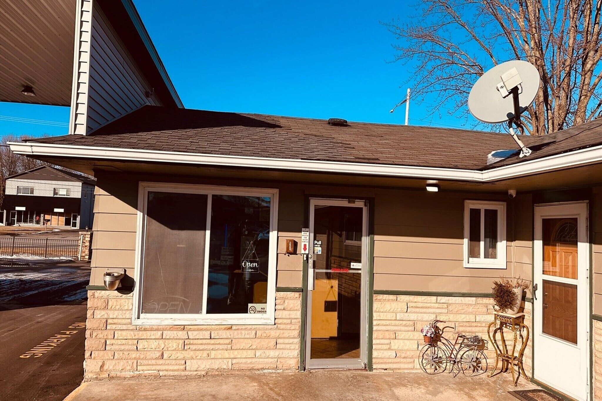 A building with a satellite dish, a bicycle, and a sign indicating a business is open.