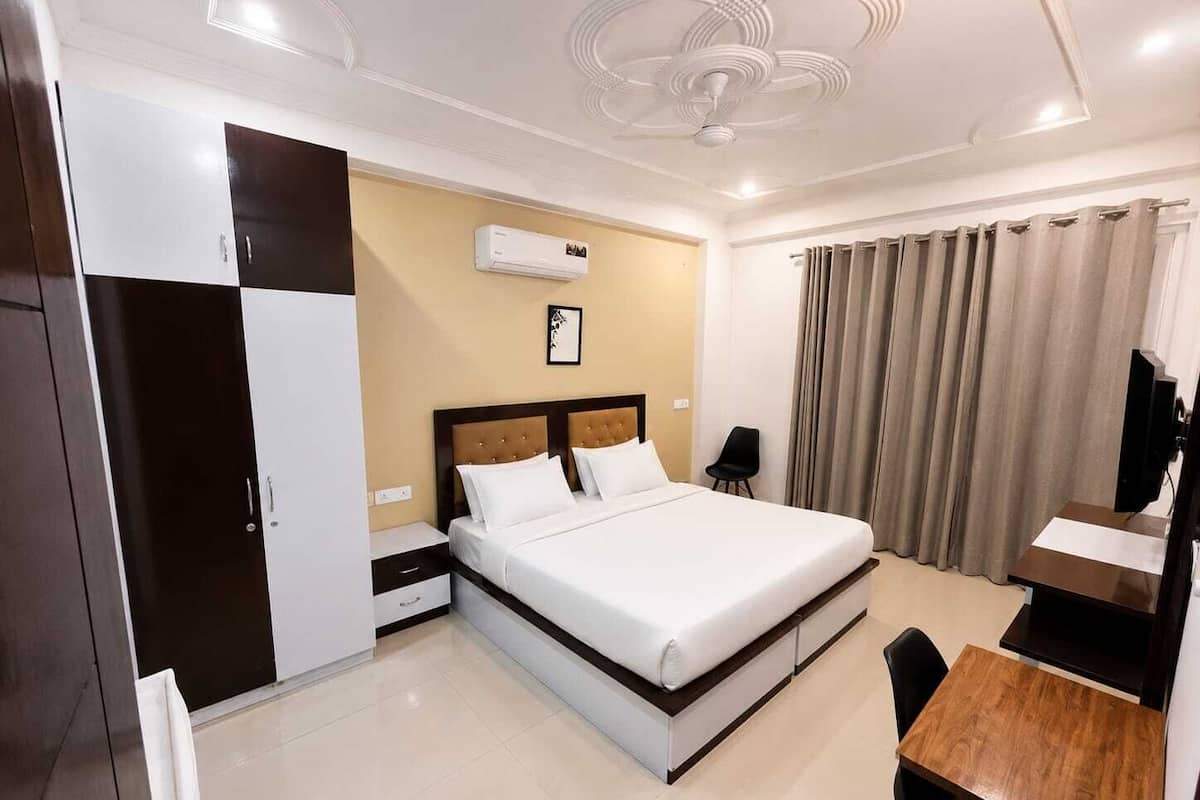 Une chambre d’hôtel équipée d’un lit, d’un bureau, d’une chaise, d’une armoire, d’un téléviseur et d’un appareil de climatisation.