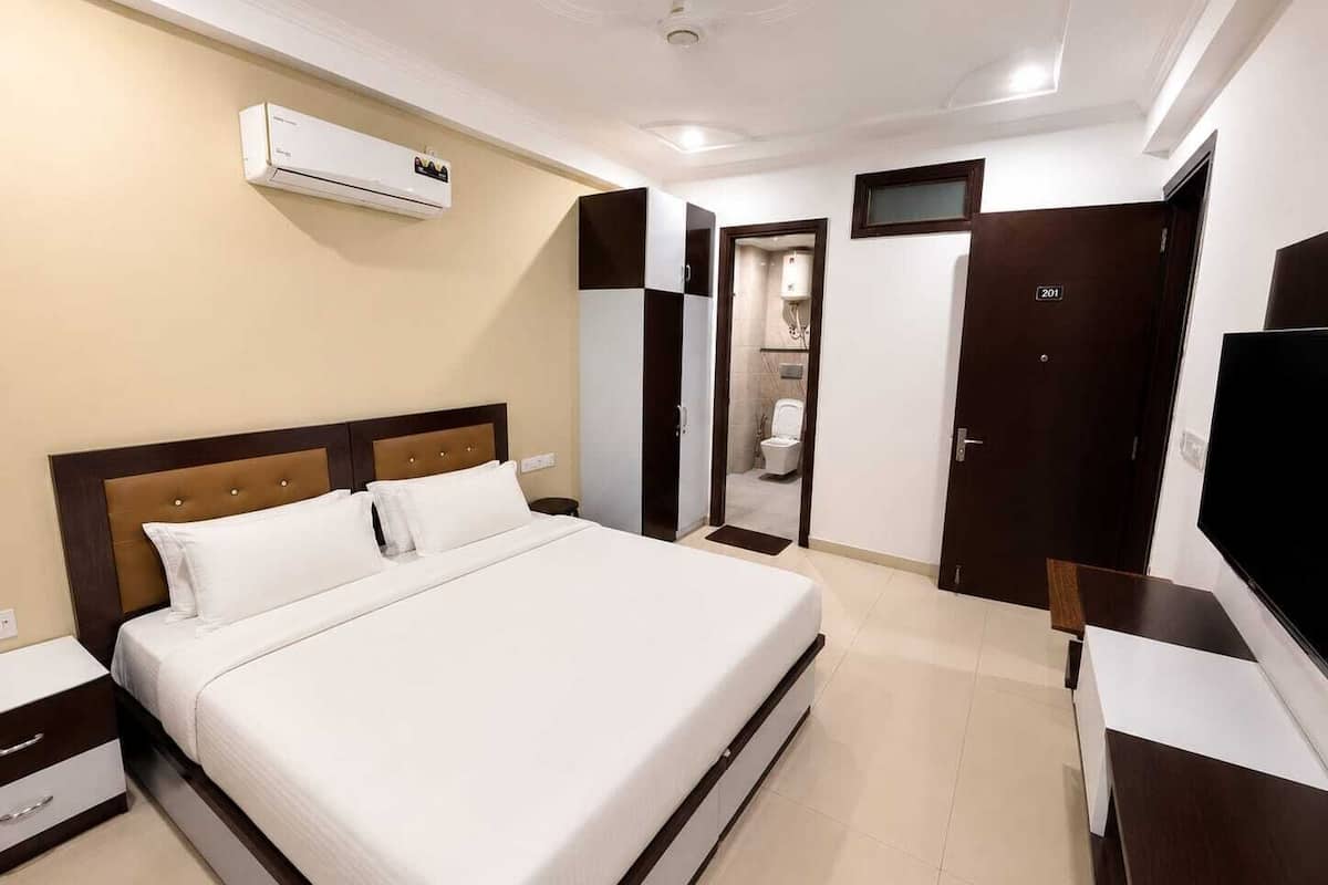 Une chambre d’hôtel équipée d’un lit, d’une télévision, d’une armoire, d’une salle de bain et d’un appareil de climatisation.
