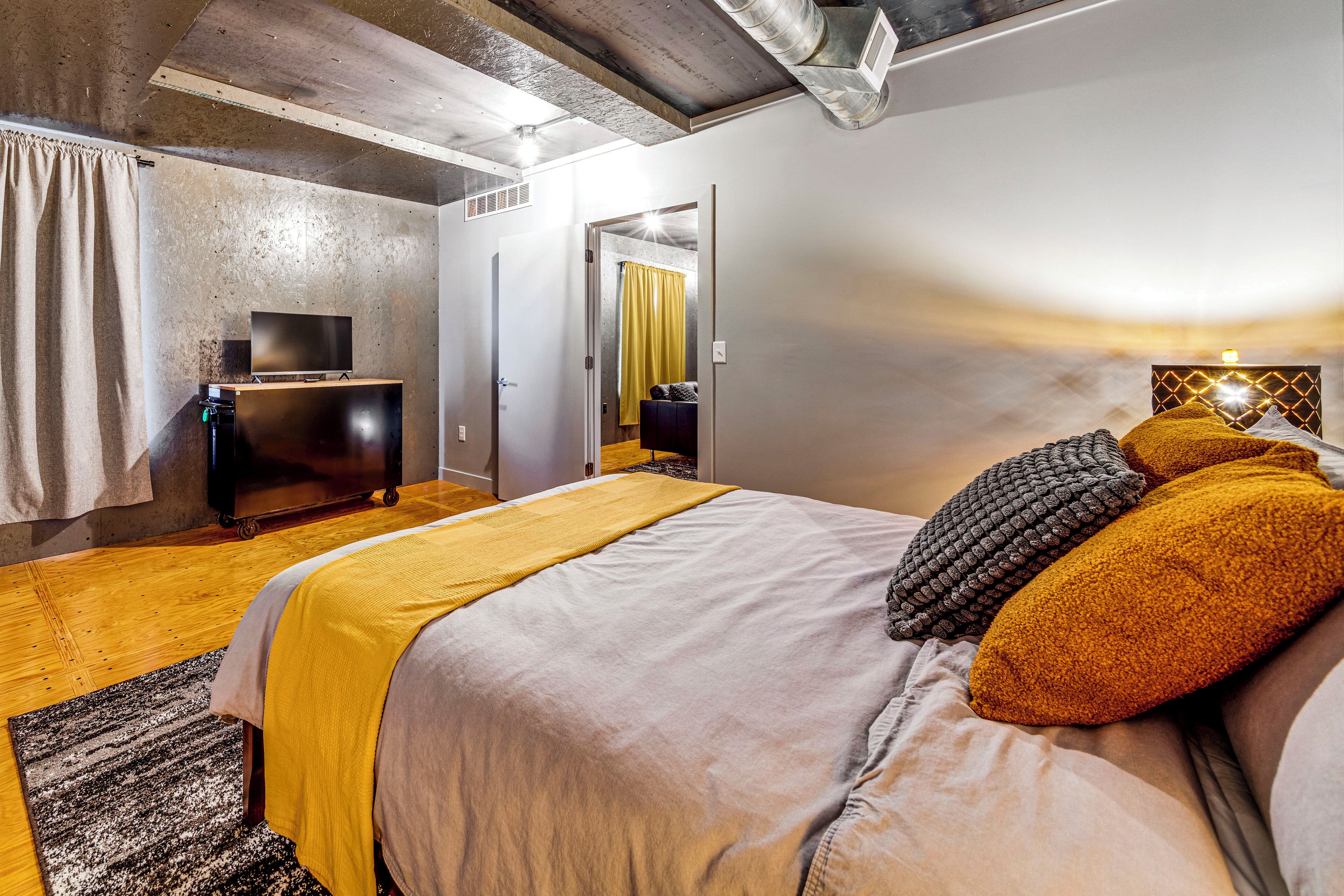 Un dormitorio con cama, televisor, armario y espejo.