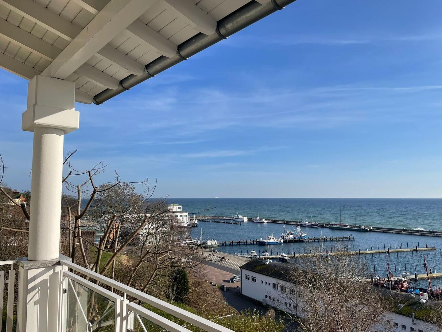 Une vue sur la côte, avec une jetée, des bateaux et un bâtiment blanc.