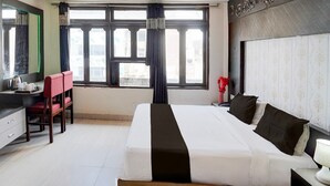 A hotel room with a bed, a desk, a chair, and a large window. - Club Kanpur Central Railway Junction (Kanpur)