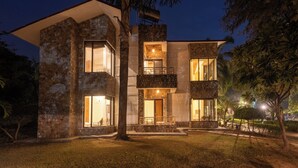 A modern multi-story building with large windows, a stone facade, and a balcony. - The Roar Resort (Ramnagar)
