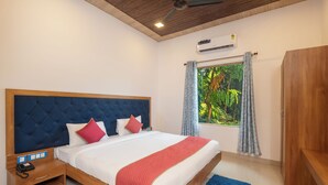 A bedroom with a bed, nightstand, and an air conditioning unit. - The Roar Resort (Ramnagar)