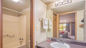 Une salle de bain avec une baignoire, des toilettes, un lavabo et un grand miroir.