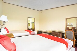 Une chambre d’hôtel avec deux lits, un bureau, une chaise, un miroir et une lampe.