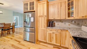 Une cuisine avec des meubles en bois, un réfrigérateur en acier inoxydable, un plan de travail en granit et une cuisinière noire.