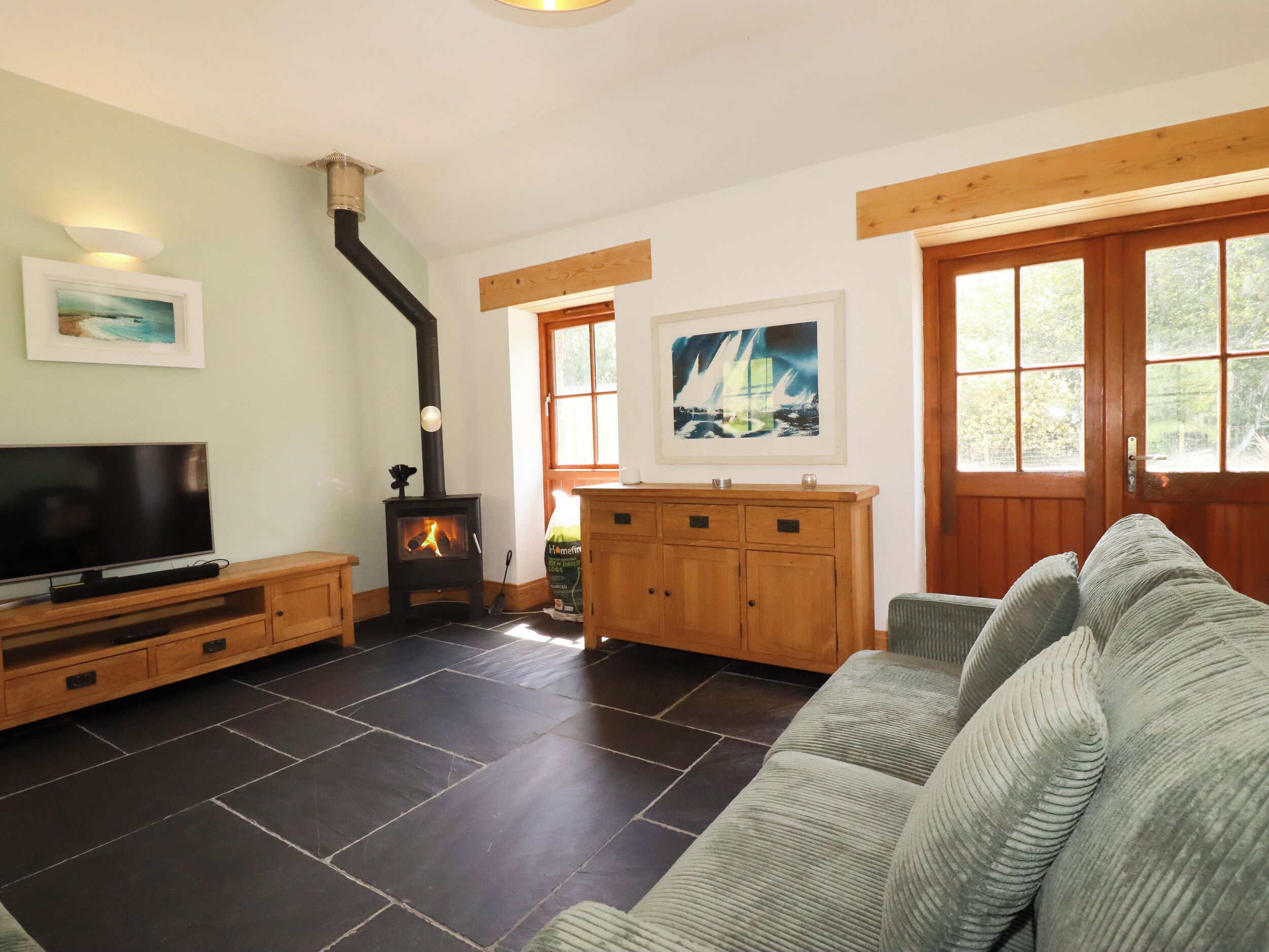 A living room with a fireplace, a television, a sofa, and artwork on the walls.