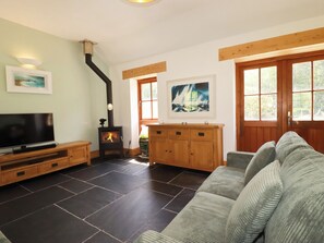 Una sala de estar con chimenea, televisor, sofá y obras de arte en las paredes.