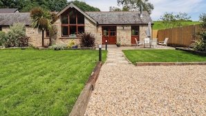 A stone house with a gravel driveway, a wooden fence, and a grassy lawn. - Little Trethellan (Redruth)