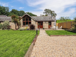 A stone house with a gravel driveway, a wooden fence, and a grassy lawn. - Little Trethellan (Redruth)