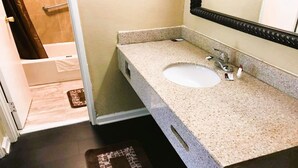 A bathroom with a sink, mirror, and shower area.