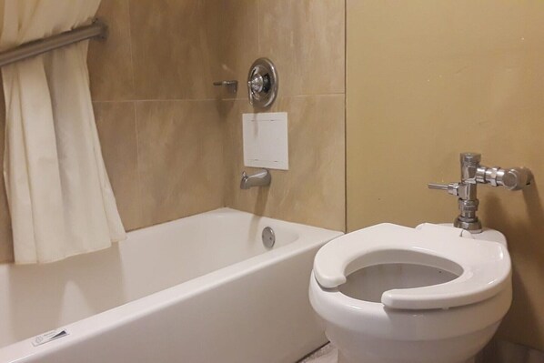 Un baño con bañera, inodoro y cortina de ducha.