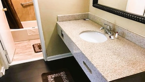 Un baño con lavamanos, espejo y zona de ducha.